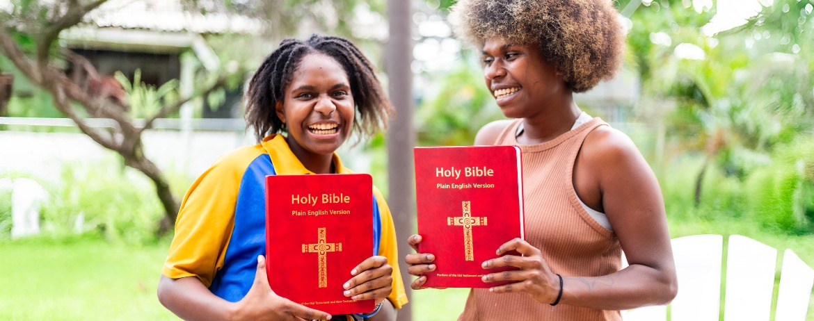Two Indigenous youth holidng the Plain English Version (PEV) Bible